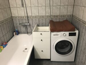 Badrummet med badkar, förvaring och tvättmaskin.